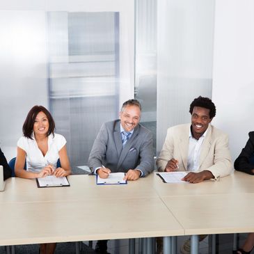 Business people in a boardroom, sitting and smiling