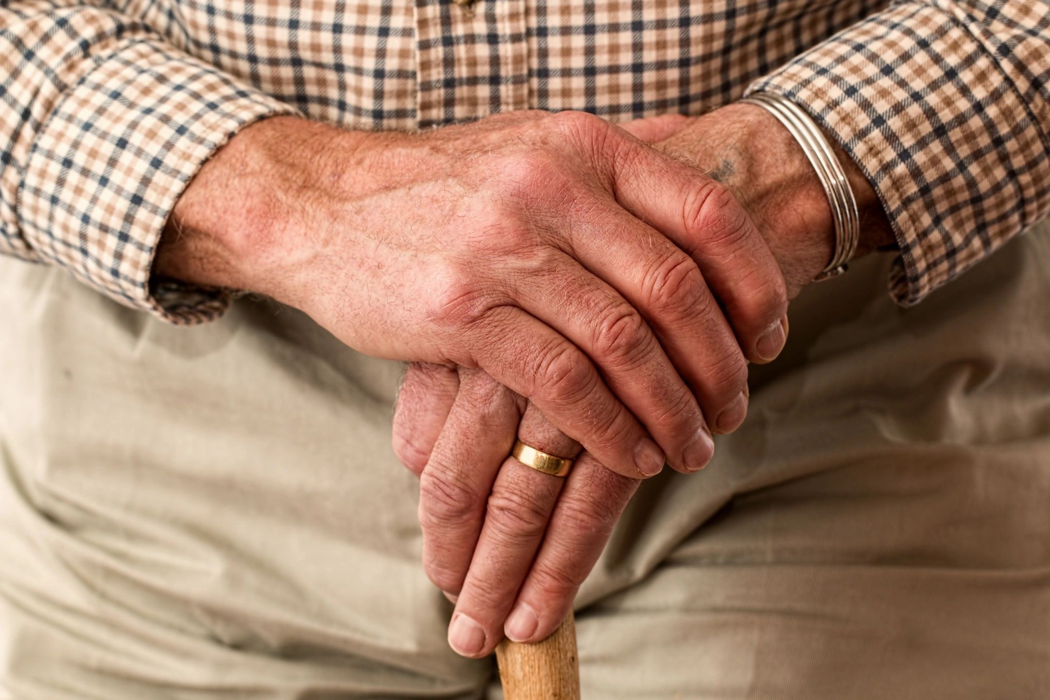 Photo showing hands of an older man holding a walking stick
