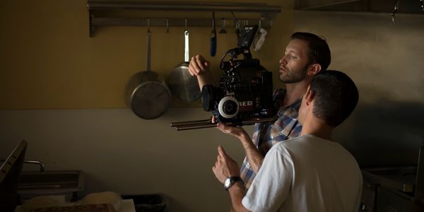 red camera being used in a production taking place in a kitchen.