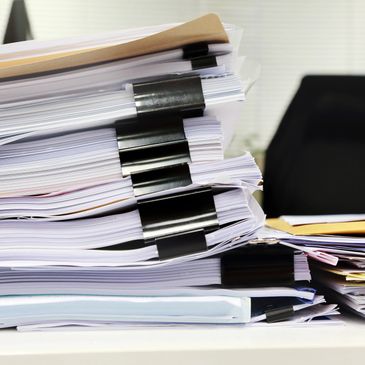 a stack of paper files on a desk ready to be scanned