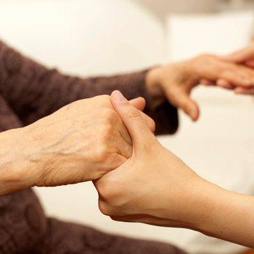 Elderly person's hands holding on to younger person's hands.