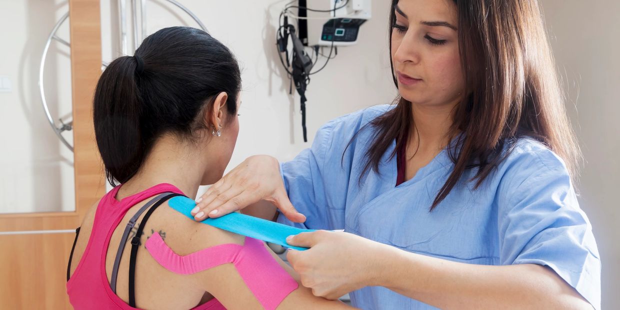 Therapist applying KT tape to a patient's arm