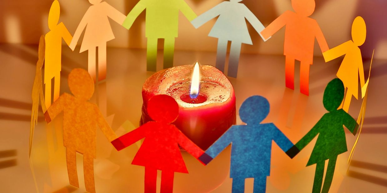 paper cutouts of people, holding hands in a circle around a candle