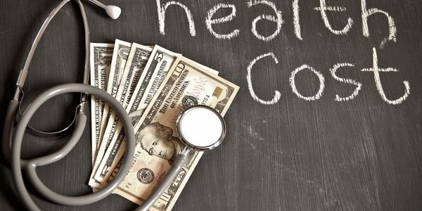 Health cost written on a surface with money and stethoscope 