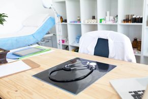 medical office desk and chair with lab coat and stethoscope. 