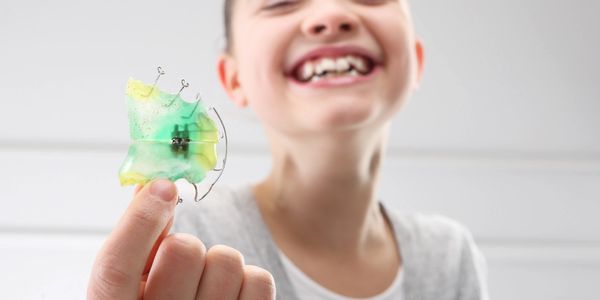 Smiling child with orthodontic retainer. 