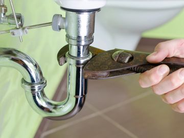 Wrench tightening a drain under a sink