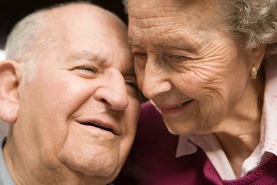 Older man and woman with their faces together lovingly. 