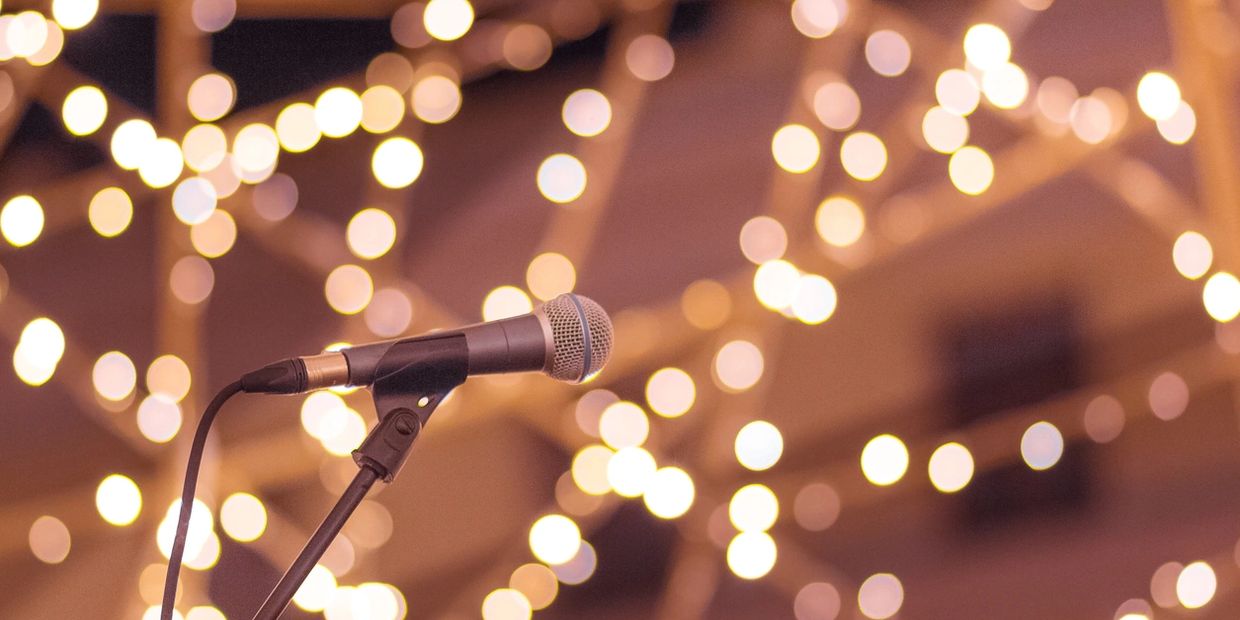 Microphone with stand, with twinkling lights in background, set up for a singer at gig