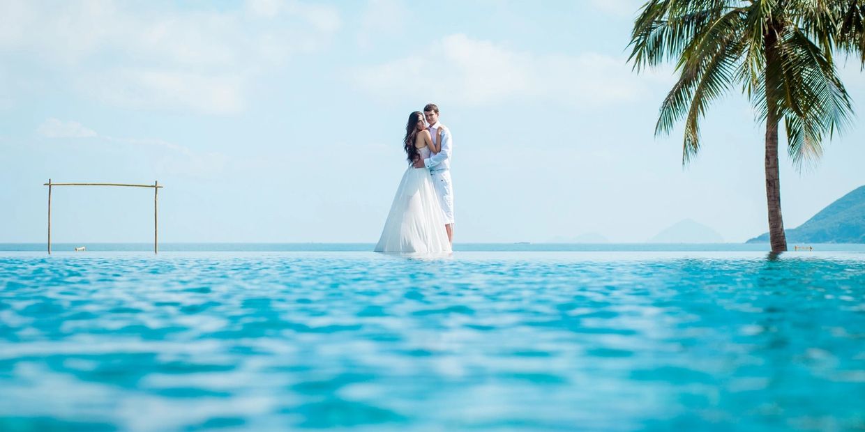 wedding couple walking on water with palm tree
