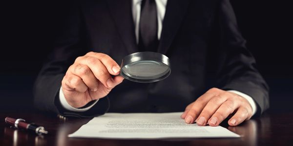 Businessman looking through a magnifying glass to documents
