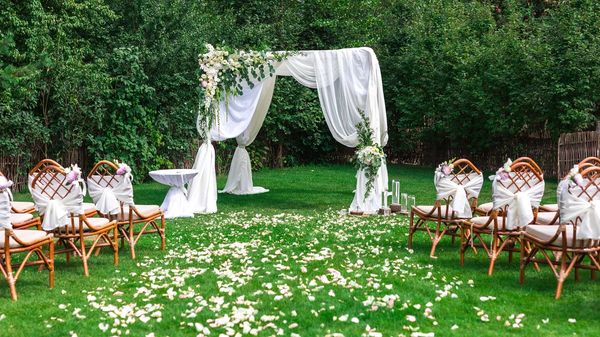 View of an archway, chairs, and flower petals set up for a ceremony