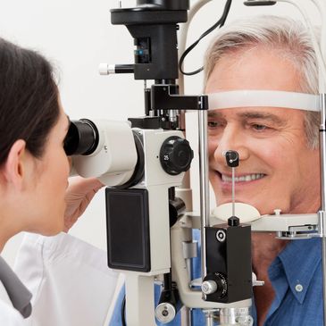 middle aged man getting an eye exam by a young optometrist using a slit lamp bio microscope  