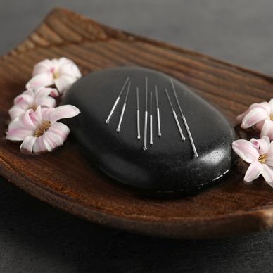acupuncture needles on stone with flower