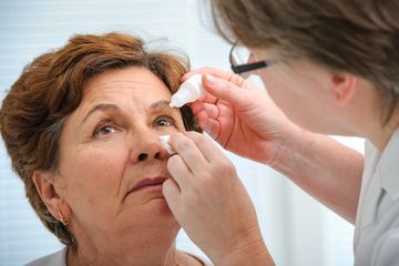 Woman patient getting eye drops from optometrist.