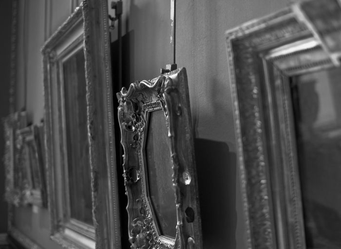 Black and white side view image of three picture frames hanging on a wall. 