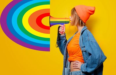 A woman shouting into a megaphone with a rainbow coming out.
