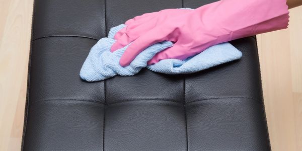 A person cleaning the top of a black pillow