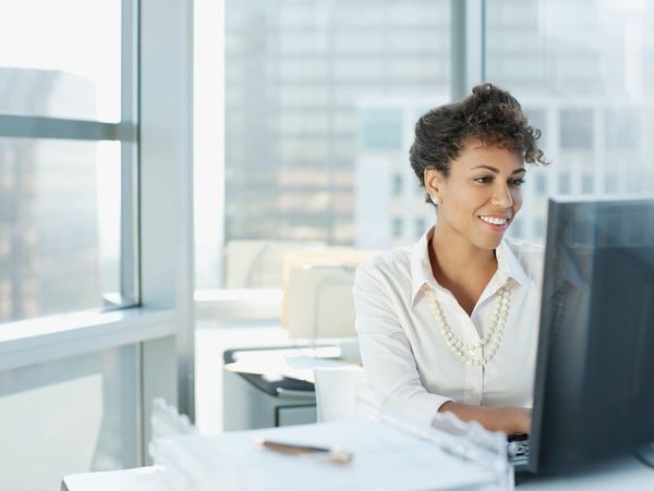 Portrait of pretty cheerful accountant looking away sitting at desk in modern office 
