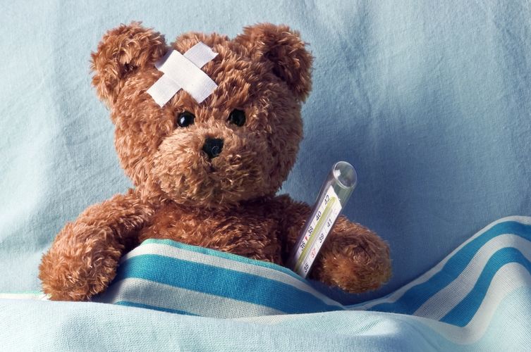 Sick teddy bear with thermometer and bandage