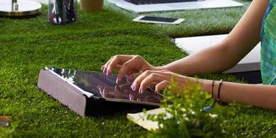Woman typing on keyboard on green grass