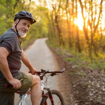 A man with his bicycle, looking back at the camera with a smile