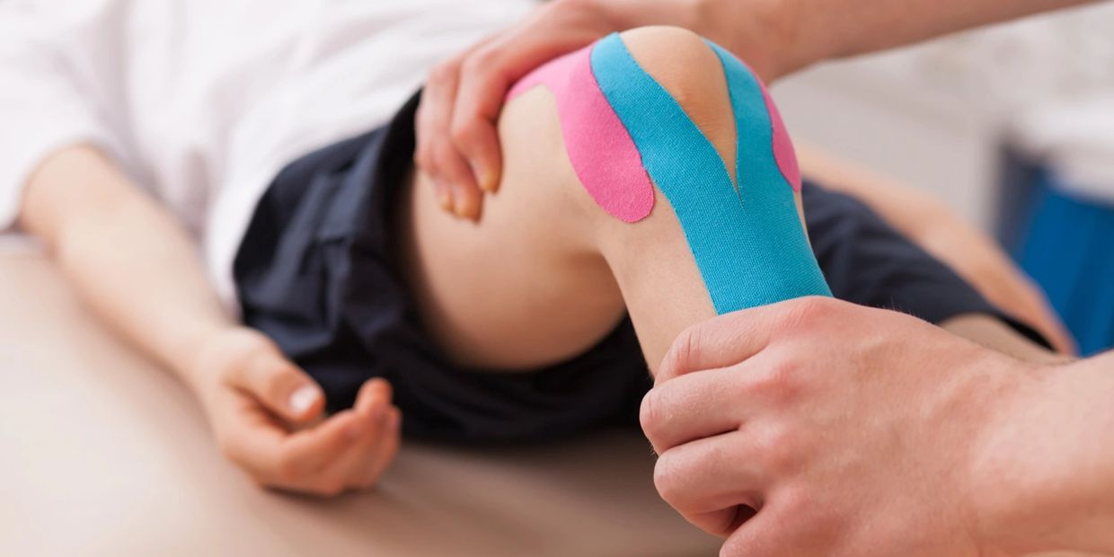 Winnipeg Physiotherapist mobilizing a patients knee with kinesiotape on the knee.