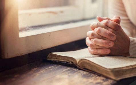 Image of praying hands an a bible.
