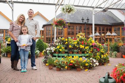 Image of parents standing in a flower-filled garden center, with their daughter standing in front of