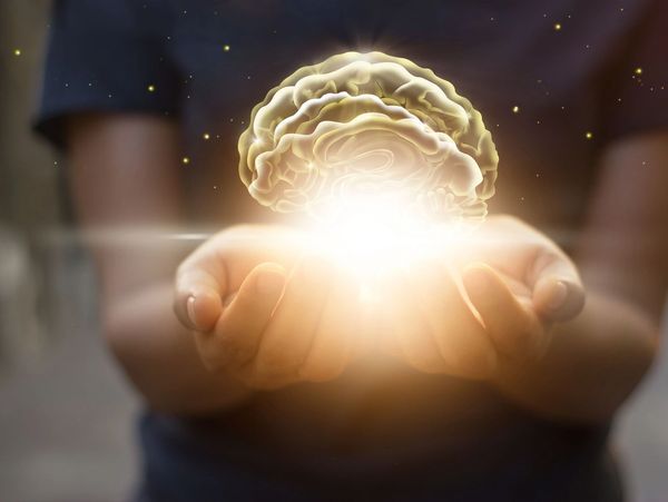 Person holding a illuminating brain on their palm