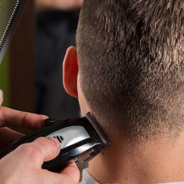 A Barber Trimming the edges of hair with a trimmer