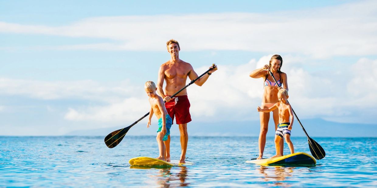 Kids riding on paddle boards with their parents