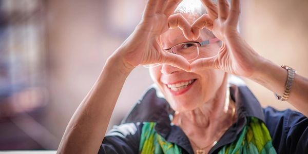 old woman making a heart shape with her fingers
