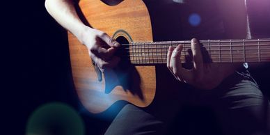 person playing acoustic guitar lens flare