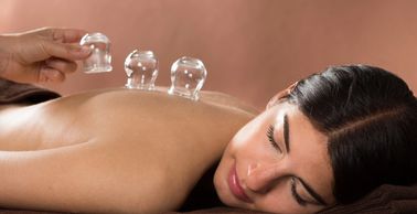 3 cups on a woman's back, woman's face and a hand placing the last cup