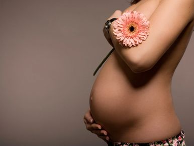 Pregnant Women caressing her stomach and holding a flower