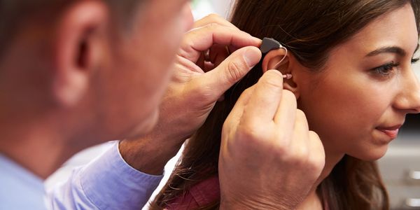 doctor fitting a woman for a hearing aid