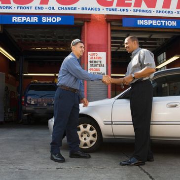 Front of car shop two men shanking hands