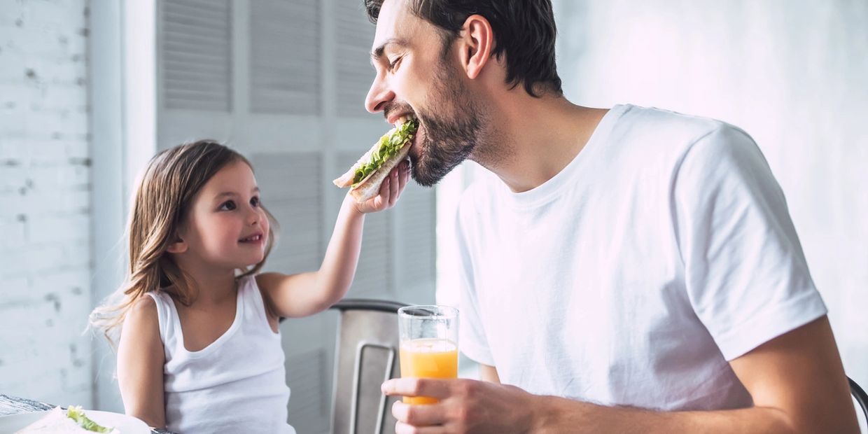picture of a kid feeding her dad a sandwich