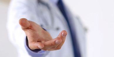 the hand of a medical professional reaching out towards the camera in a helpful gesture