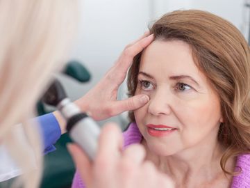 Practitioner examining eye of woman patient.