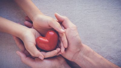Two people using their hands to hold a heart