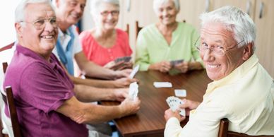 Senior citizens playing cards at a table in a retirement home