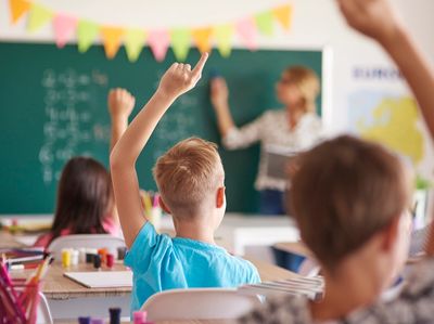 Children raising hands in a classroom