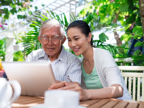 a woman and a elderly man looking at the laptop