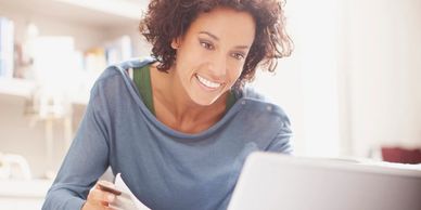 Stock photo of person sitting on white chair with computer and papers 