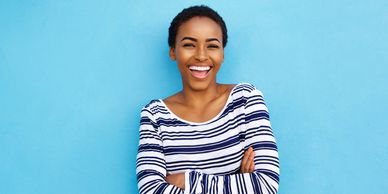 Smiling black woman with stripped sweater and baby blue background. Black disabled lives matter