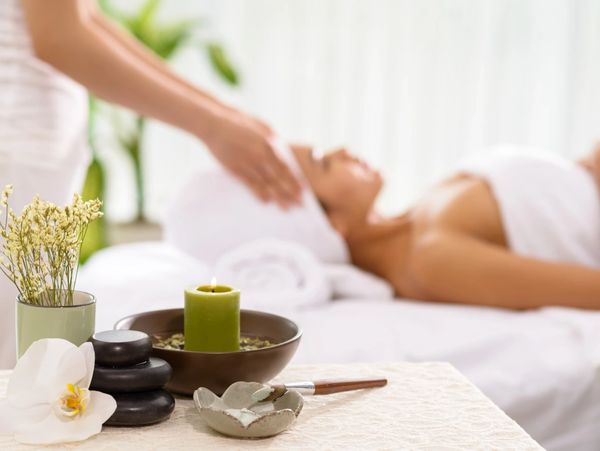 A woman having a relaxing head massage in a friendly and clean clinic with candles and aroma.