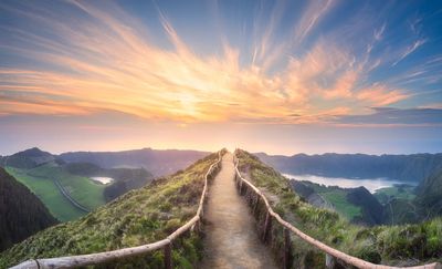 Pathway on the top of a mountain. Viewer can see a yellow sunset.