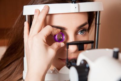 a woman in a slit lamp getting her eyes examined